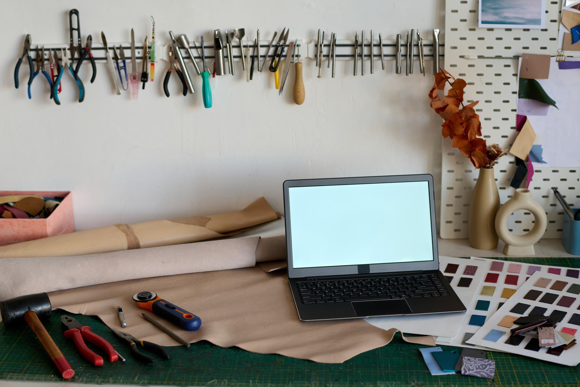 Tavolo di lavoro con campioni di ricamo e laptop